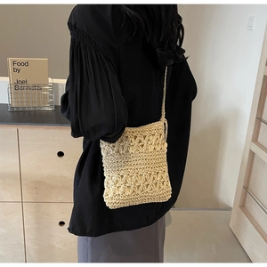 Detail of hand-woven straw bucket bag featuring intricate floral hollow patterns