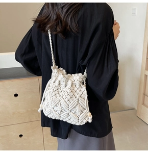 Detail of white woven bucket bag with drawstring closure and decorative wooden beads