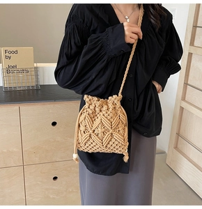 Detail of hand-woven straw bucket bag featuring drawstring closure and wooden beads