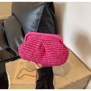 Detail of rose red woven texture and fine gold chain strap on straw clutch bag