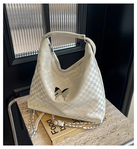 Detail of white checkered hobo bag with silver butterfly buckle and chain strap