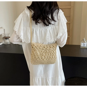 Detail of star-patterned straw bucket bag with adjustable shoulder strap and inner lining