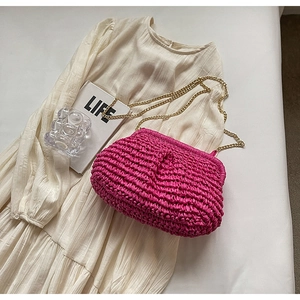 Detail of fuchsia woven shell bag with gold chain strap on minimalist background