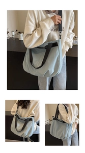 Detail view of light blue canvas tote bag showing wide black straps and side pleats