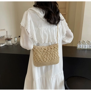 Detail of hand-woven straw bucket bag with star patterns worn as a crossbody by a model
