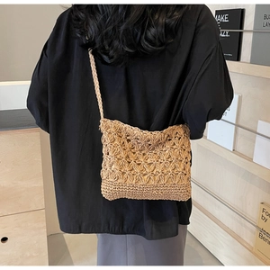 Detail of hand-woven straw crossbody bag with floral cutouts and fabric lining