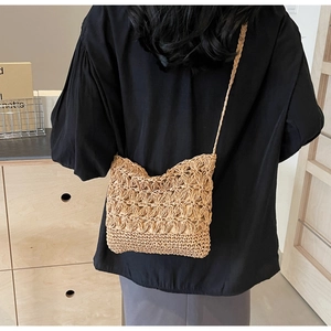 Close-up of hand-woven straw bucket bag showing hollow floral texture and thin strap