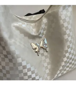 Macro shot of liquid metal butterfly charm and checkered pattern on a tote bag