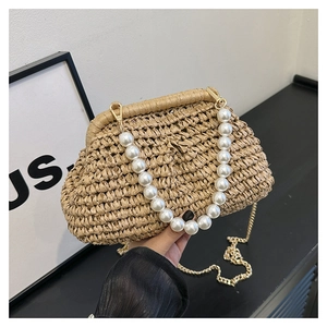 Detail of straw woven bag featuring large pearl handle and golden chain shoulder strap