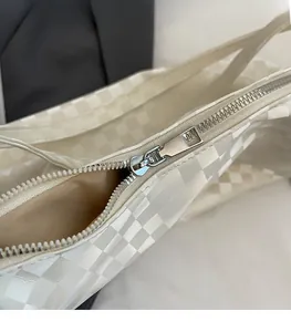 Detailed macro view of silver zipper and white checkered leather texture on tote bag