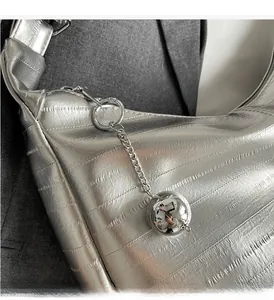 Détail du sac à bandoulière argenté texturé avec chaîne en métal et breloque sphère