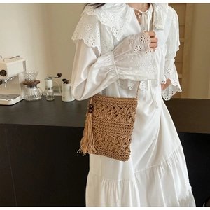 Close-up of woven straw bucket bag with flower crochet patterns and long tassels with beads