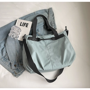 Detail of mint green tote bag featuring adjustable black straps and durable canvas texture