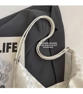 Detail of adjustable shoulder strap and silver buckle on white checkered leather bag