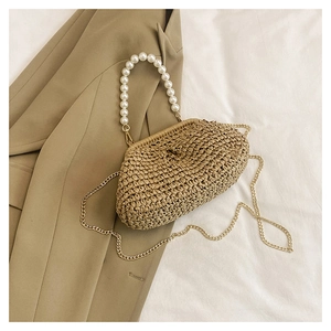 Close-up of straw woven crossbody bag with white faux pearl handle and gold chain strap