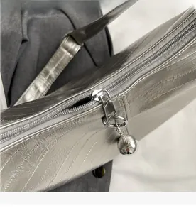 Détail du sac argenté métallisé avec fermeture éclair fluide et breloque sphérique