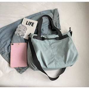 Detail of light blue tote bag with black straps alongside a tablet and denim jacket