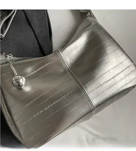 Détail du sac hobo argenté avec texture plissée et ornement de breloque ronde