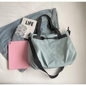 Flat lay of a mint green canvas tote bag with black straps and casual life accessories