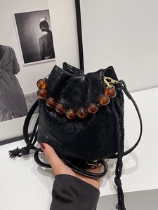 Fashionable black pleated bucket bag with amber beaded handle and long shoulder strap
