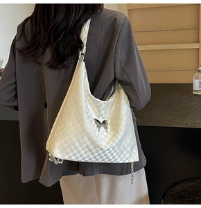 Detail of cream checkerboard tote bag featuring silver butterfly clasp and chain accents