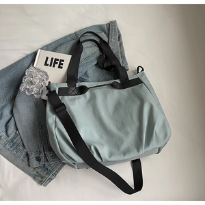 Close-up of mint green tote bag with black straps and detachable shoulder strap detail