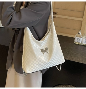 Detail of checkered woven tote with silver metallic bow and chain strap accents