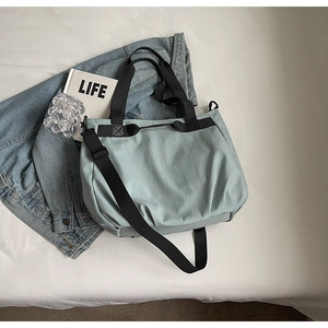 Detail view of reinforced stitching and black straps on a light blue casual tote bag