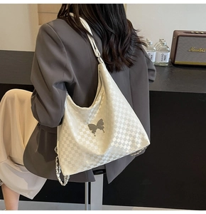 Detail of white checkered hobo bag with silver butterfly charm and chunky chain strap