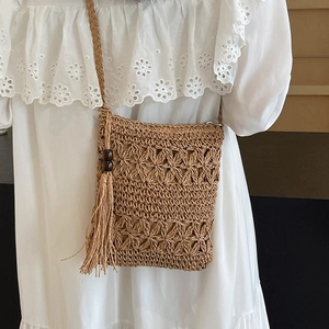 Handwoven straw bucket bag with floral hollow design and tassel accents for beach fashion