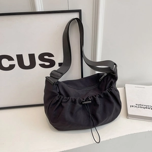 Sac bandoulière plissé noir minimaliste avec large sangle et design à cordon coulissant