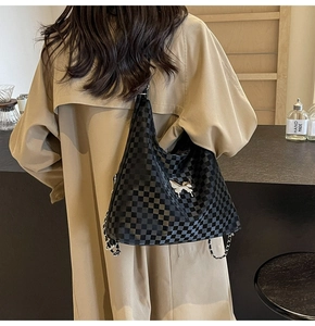 Detail of checkered tote bag with silver butterfly charm and chain shoulder strap