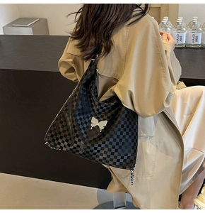 Detail of checkered tote bag featuring silver butterfly clasp and metal chain strap