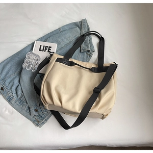Detail of beige canvas tote bag with pleated texture and adjustable black crossbody strap