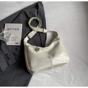 Détail du sac bandoulière crème avec texture crocodile et breloque sphère argentée