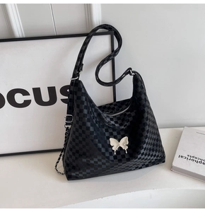 Detail of black checkerboard hobo bag featuring 3D white butterfly and metal chain strap
