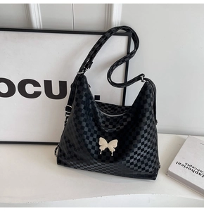 Detail of black checkerboard crossbody bag featuring a white 3D butterfly accessory