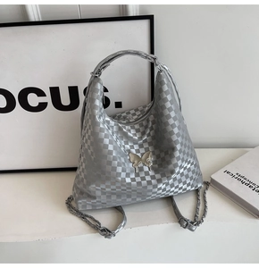 Silver checkered tote bag detail featuring metallic butterfly ornament and chain strap