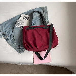 Detailed top view of wine red nylon tote bag with black handles and lifestyle props