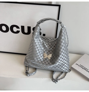 Close-up of silver checkerboard tote bag with metal butterfly charm and chain strap