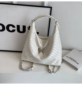 Close-up of white checkerboard bag with silver metal butterfly and chain strap detail