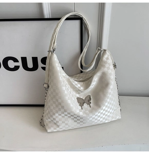 Close-up of cream checkerboard tote bag featuring silver butterfly metal ornament