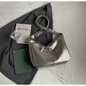 Détail du sac argenté métallisé avec texture plissée et pendentif sphérique chic