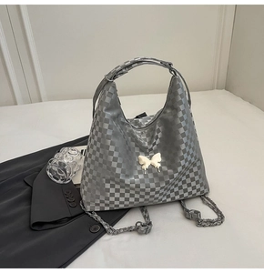 Silver-grey checkered hobo bag with white butterfly detail and chain strap on grey blazer