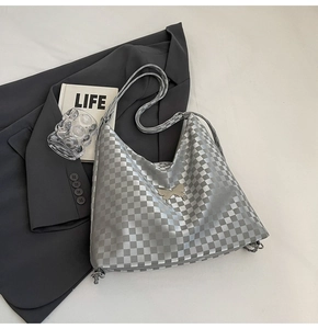 Detail of silver checkered hobo bag with metallic bow charm and adjustable strap
