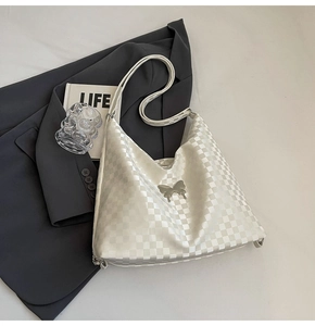 Detail of white checkerboard tote with silver butterfly buckle on a dark suit