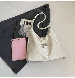 Close-up of white checkerboard hobo bag with silver butterfly charm and glossy finish