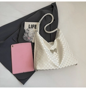 Detailed view of white checkered tote bag with metal butterfly clasp and lifestyle props