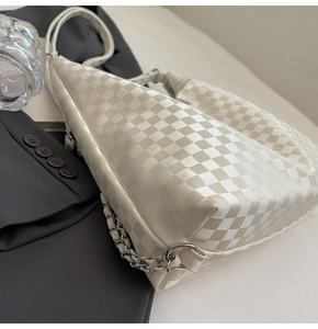 Close-up of cream checkerboard shoulder bag featuring textured leather and silver chain