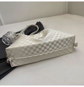 Detail shot of a beige checkerboard tote bag with metal buckle and silver brand logo